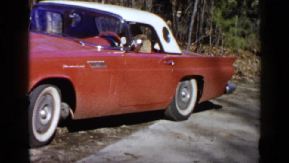 The red and white 1957 Ford Thunderbird is shown in profile on a rural-looking roadside near Birmingham, Alabama.