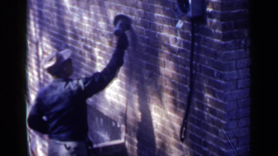 The final frame shows the worker reaching higher on the Birmingham brick wall, with 8mm grain and strong side light.