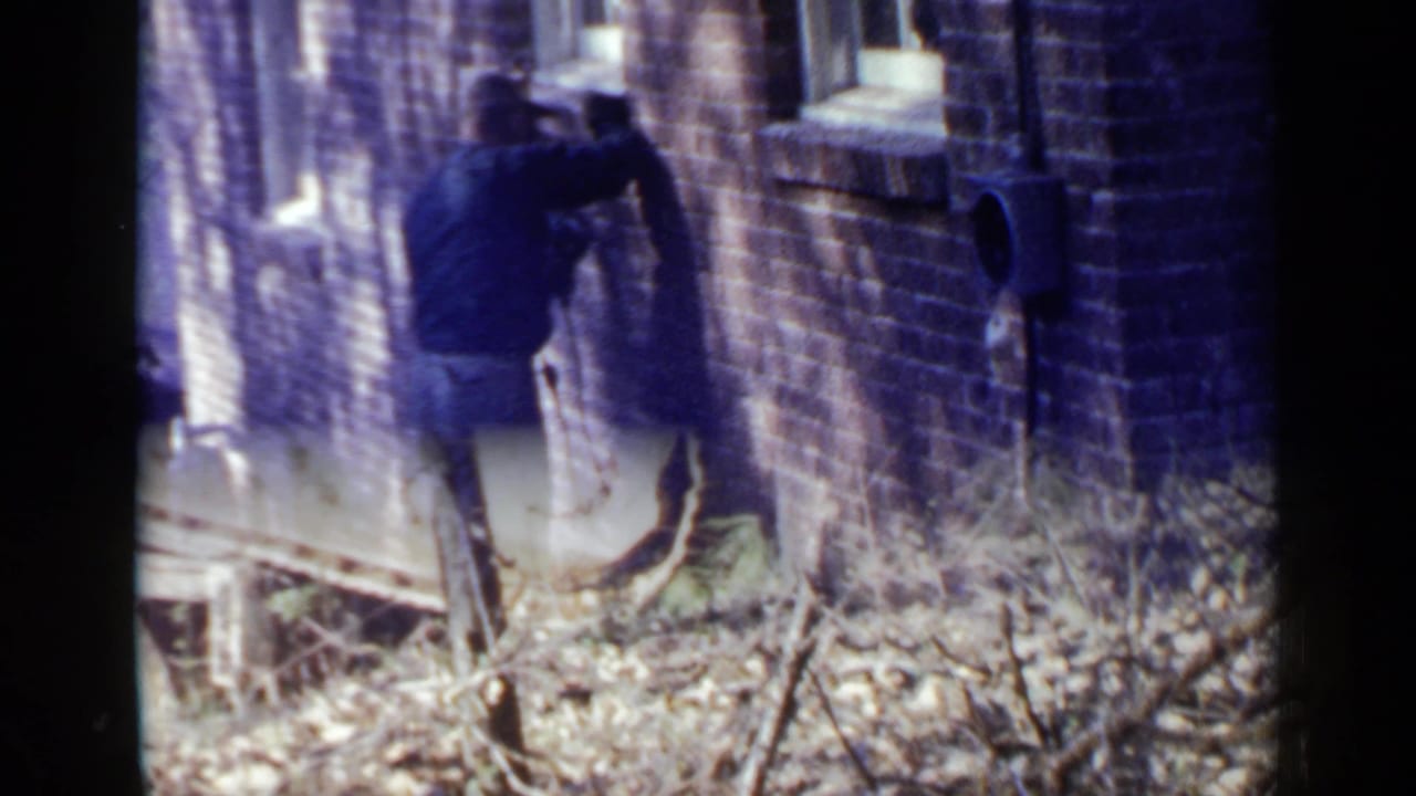 Man climbing a ladder beside a brick wall in a narrow alley.