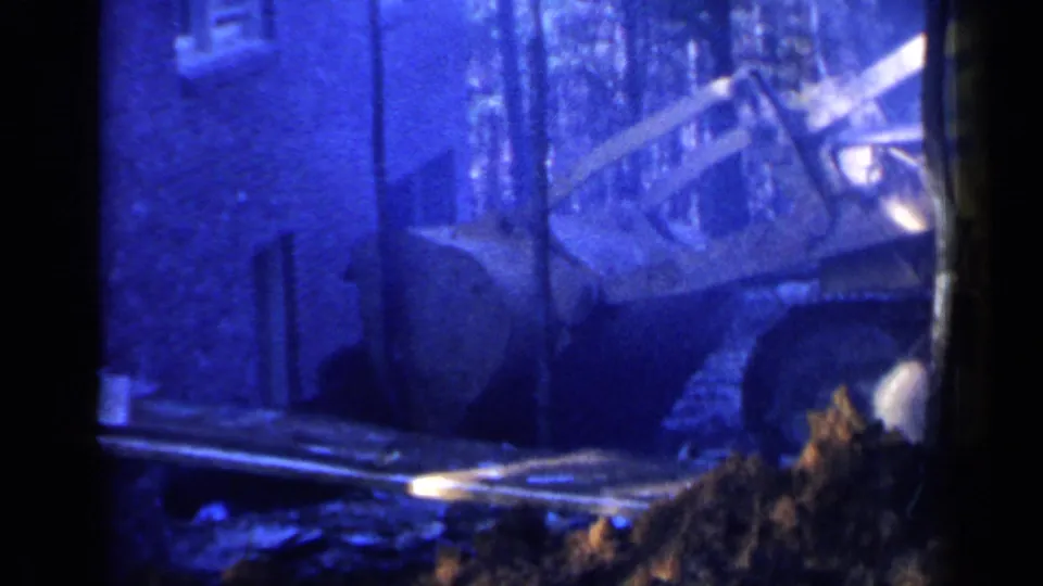 1957 Birmingham 8mm frame showing a bulldozer at a construction site beside a building, with a dirt pile in the foreground.