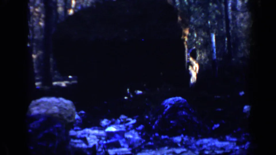 End frame from the 1957 Birmingham 8mm clip, with shadowed earth, scattered debris, and part of the work area in heavy blue cast.
