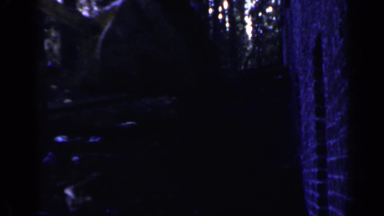Dark blue-tinted view of industrial machinery or structure in heavy shadow.