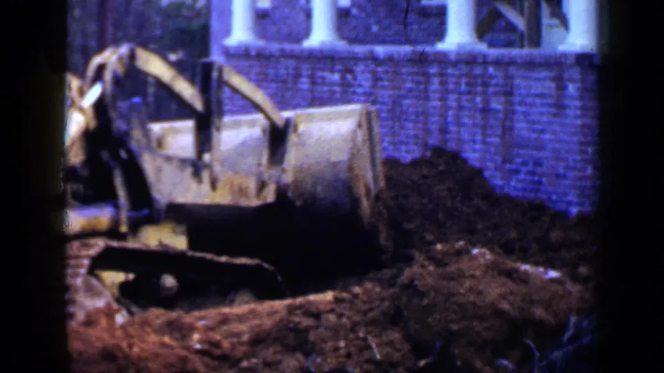 The bulldozer faces a large dirt mound outside a brick Birmingham residence in the 1957 footage.