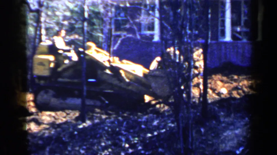 A man operates a crawler bulldozer with its blade extended in a wooded Birmingham residential lot in 1957.