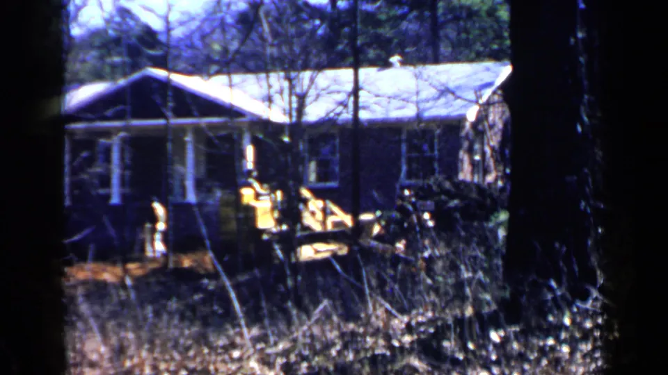 Home-movie still of a yellow front-end loader working beside a wooded house lot in Birmingham, Alabama, 1957.