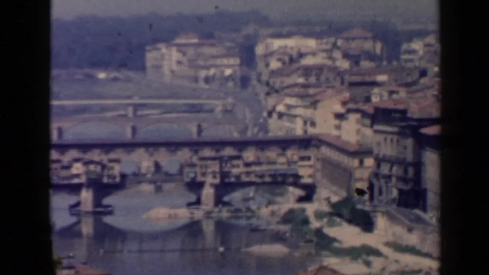 1960s 8mm panorama of the Arno River in Florence, with bridges, riverside buildings, and distant hillside structures.
