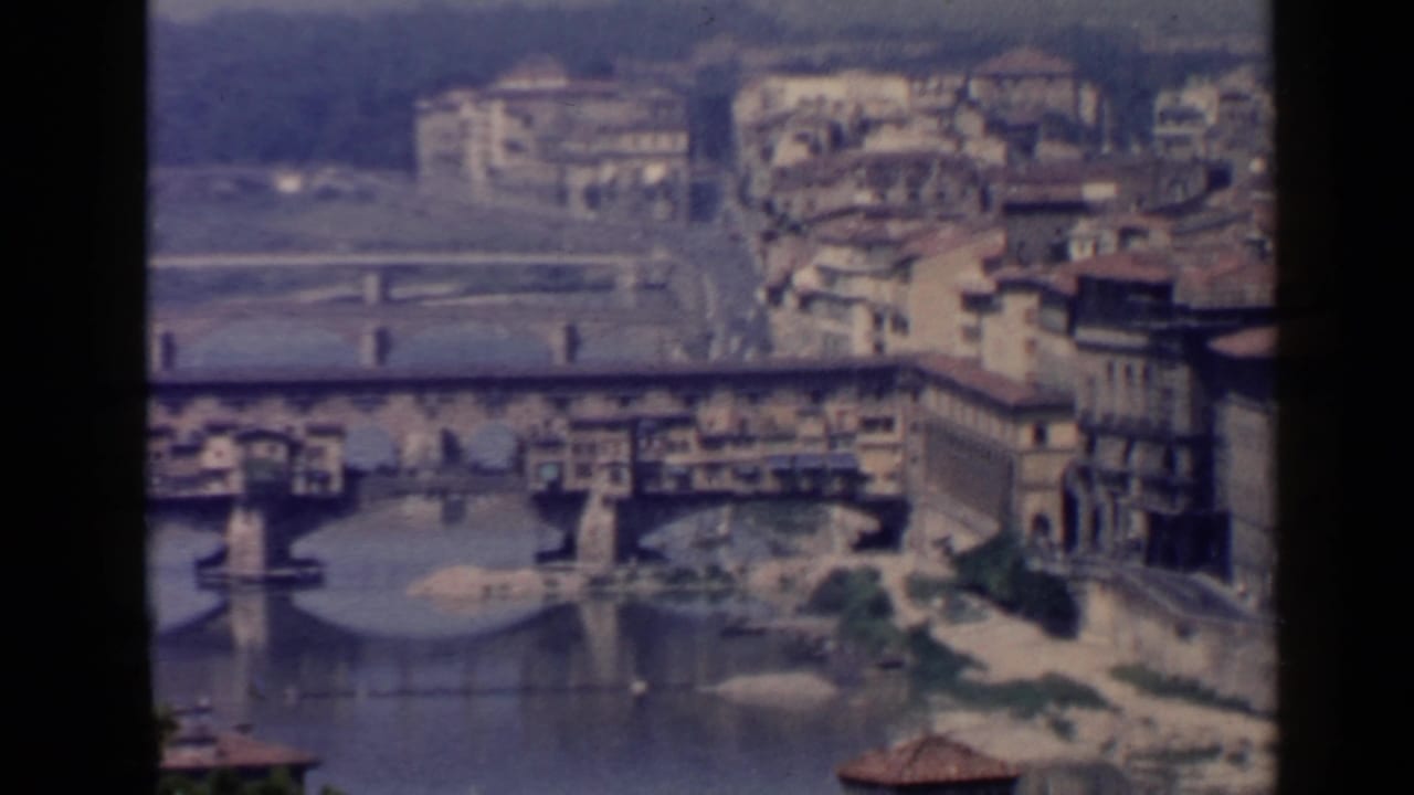 Ponte Vecchio spanning the Arno River with riverside buildings beyond.