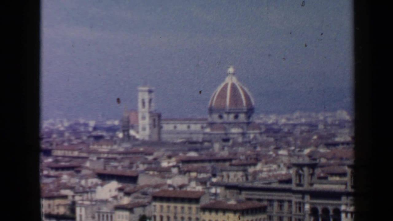 Distant Florence skyline with cathedral dome, bell tower, rooftops, and dark film borders.