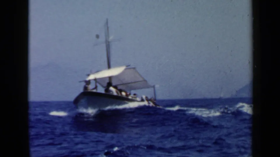 The passenger motorboat appears farther from the camera, pitching through open sea with a visible wake and canopy.
