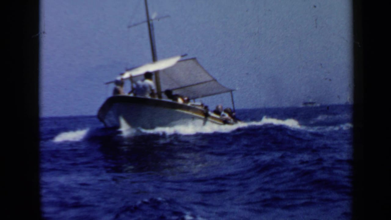 Canopy tour boat carrying passengers across blue choppy water.
