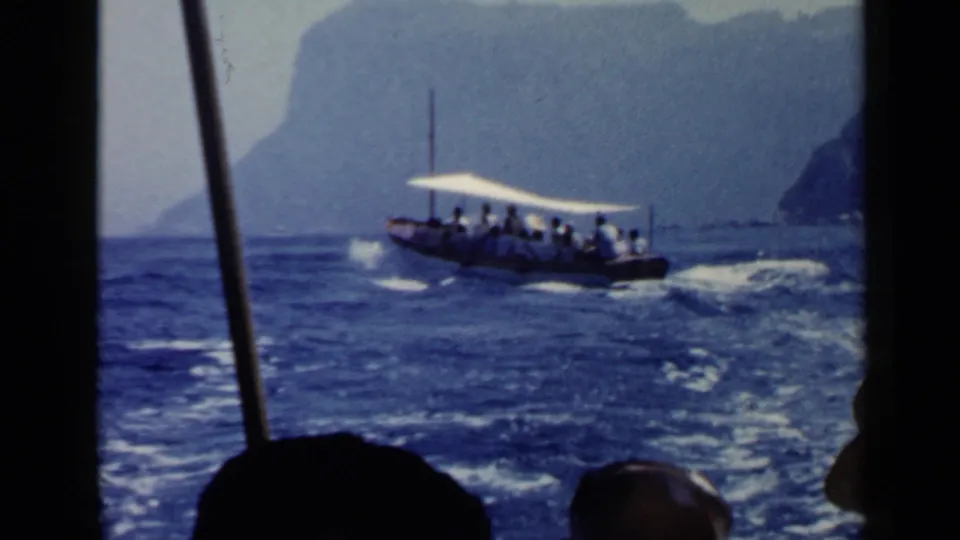 Canopy boat with passengers travels across choppy water near the Rome-area coast in a soft 8mm frame.