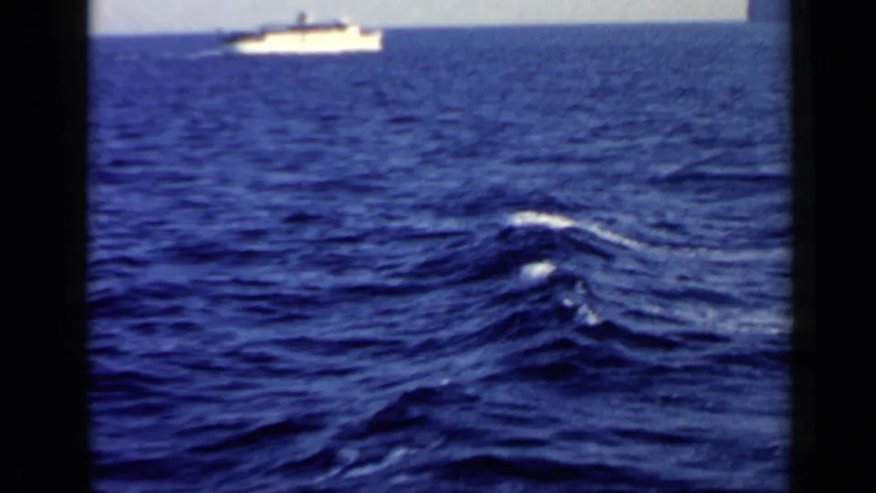 1960 8mm sea view near the Italian coast, with a distant vessel and visible wake on deep blue water.