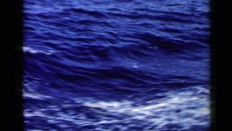 1960 8mm Rome-area seascape with dark swells, streaks of white foam, and a distant white vessel at the horizon.