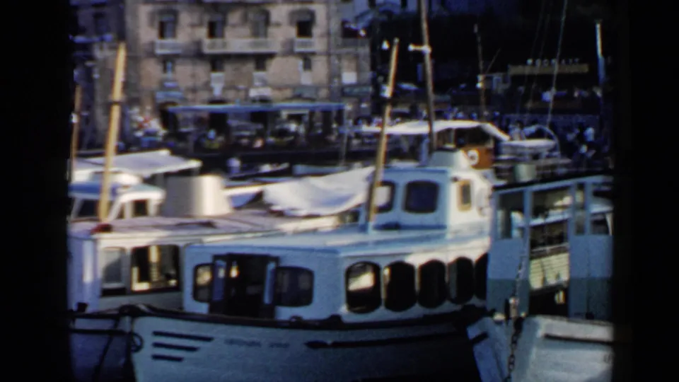 A 1960 Rome harbor view shows white boats and rigging in front of waterfront buildings, with a bus visible in the distance.