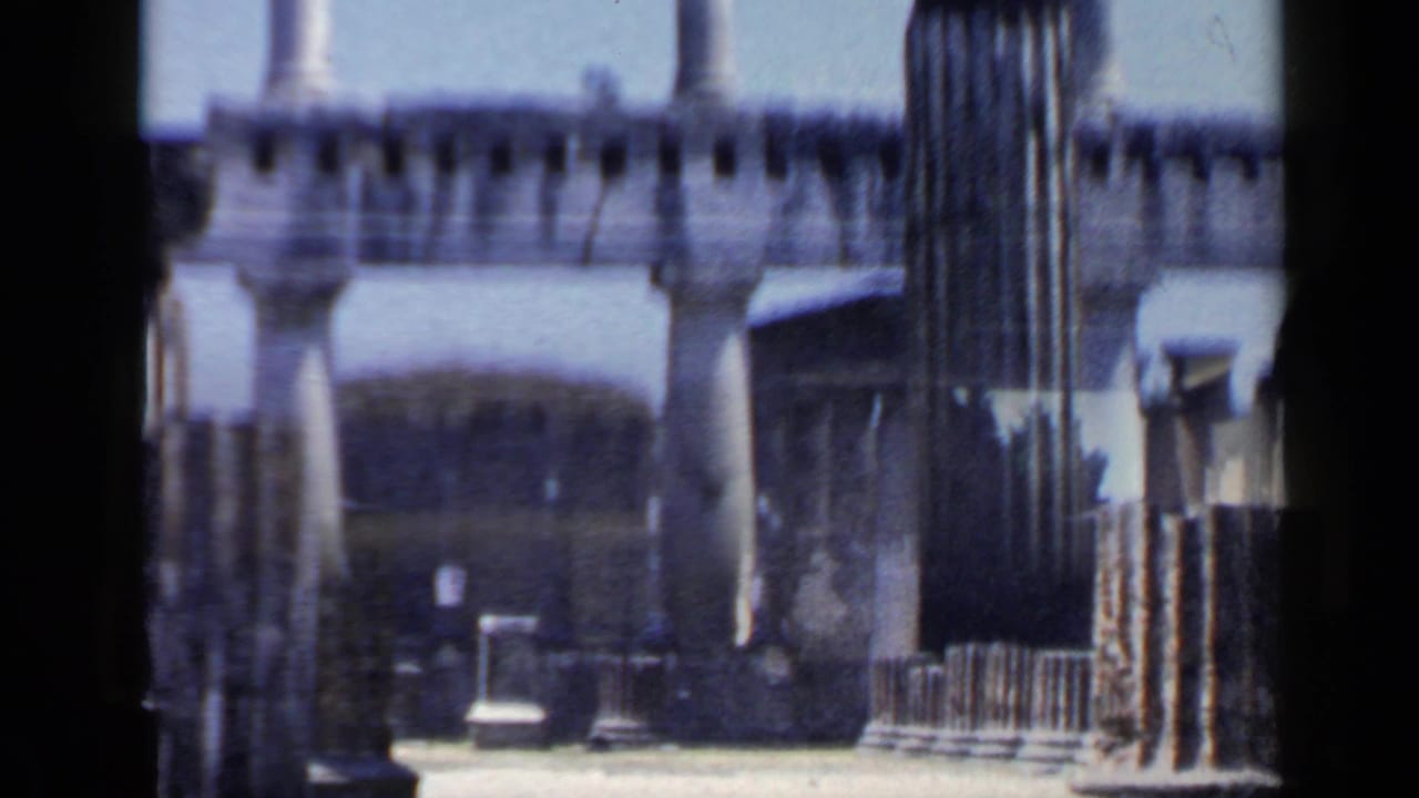 Stone columns and ruined walls seen through dark film-edge framing.