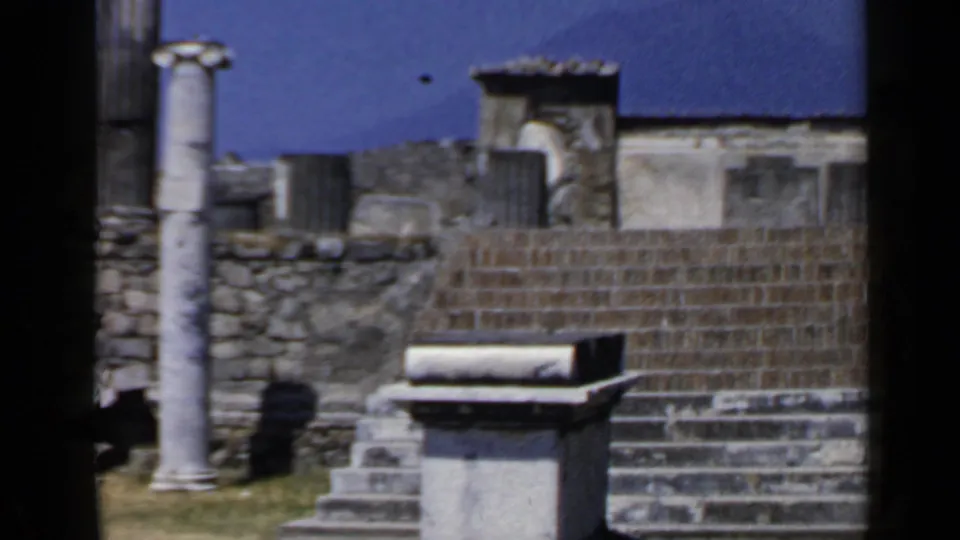 1960 Rome 8mm frame showing stone staircases, column fragments, weathered walls, grass, and dark film-edge borders.