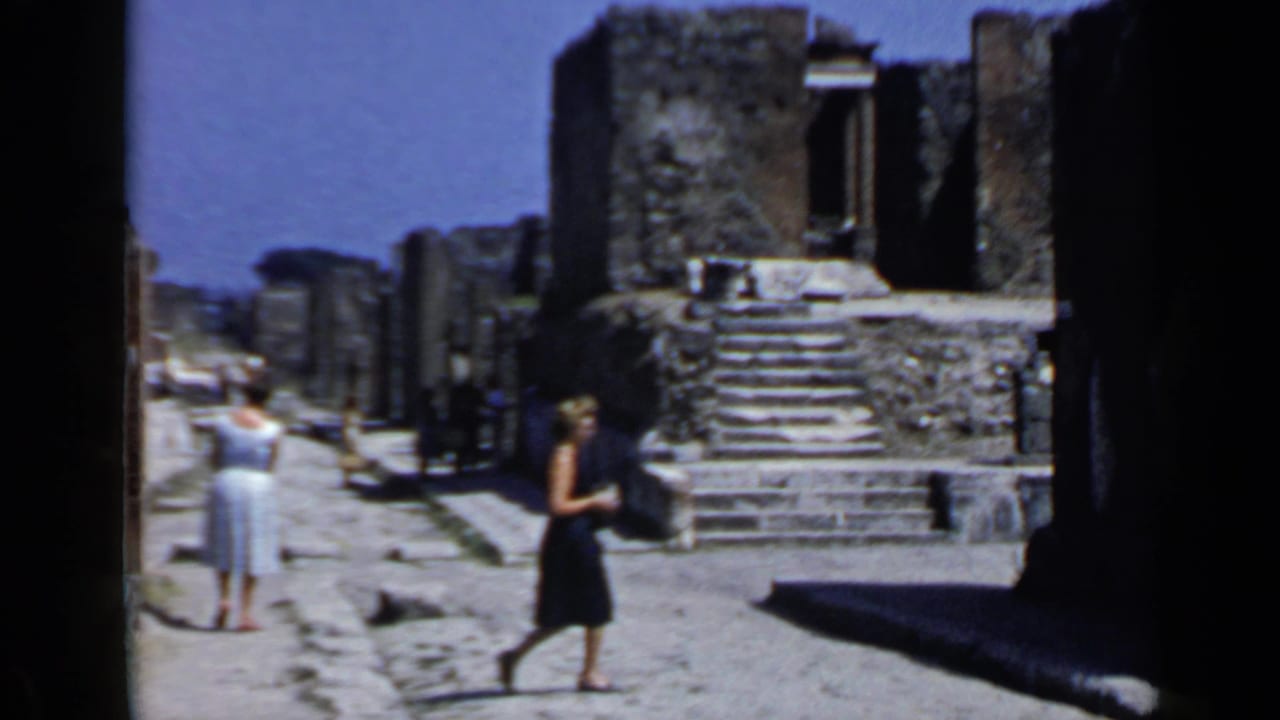 Tourists walking through stone ruins under a blue sky.