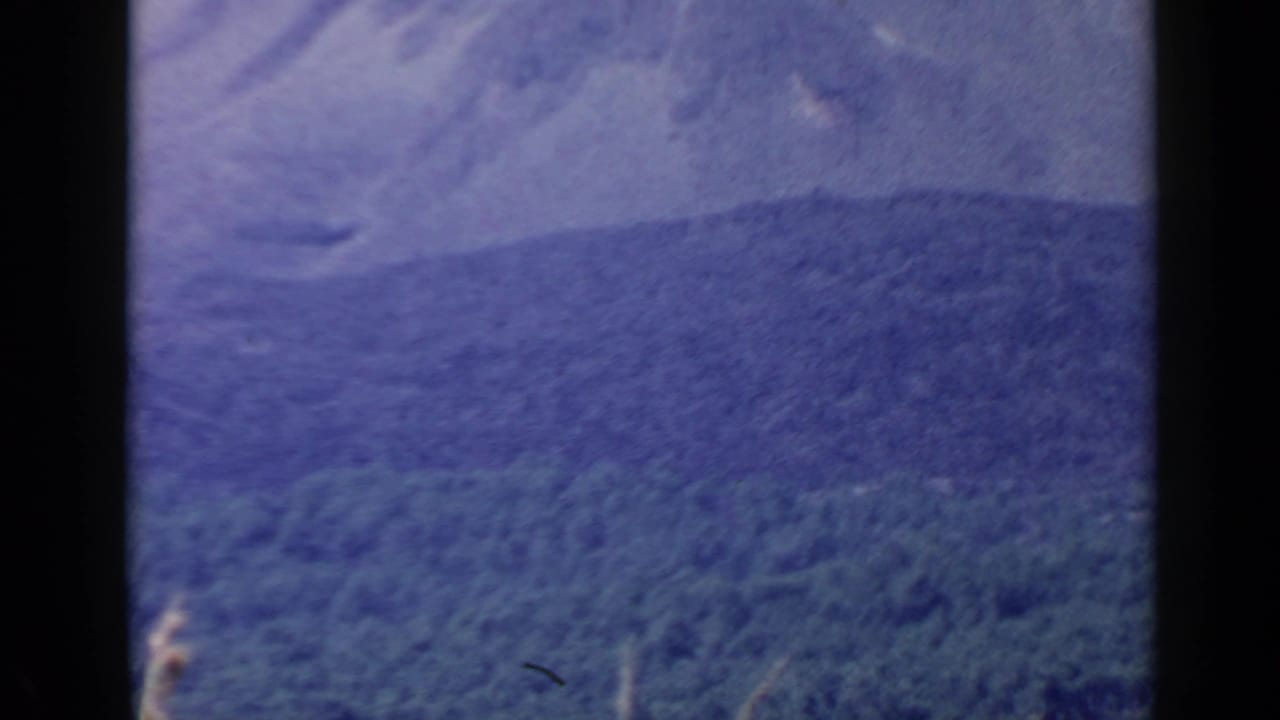 Soft 8mm frame showing a distant wooded ridge and hazy mountain form in the Rome, Italy travel sequence.