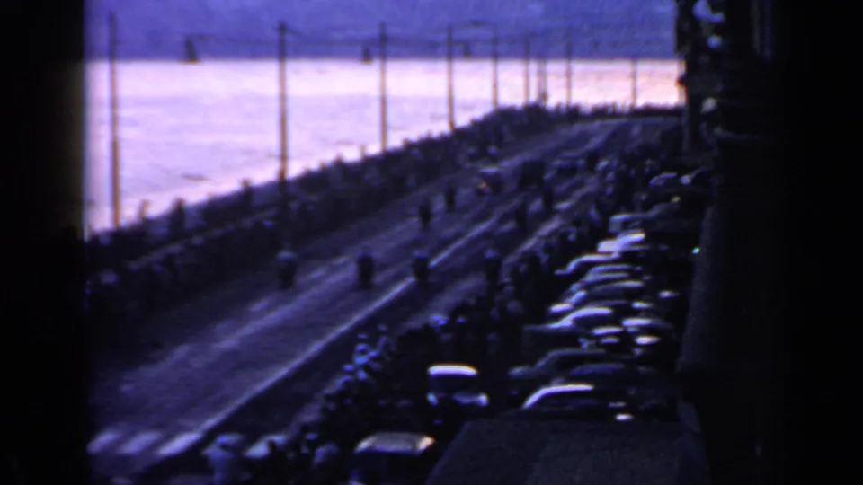 Rome 1960 Olympic torch parade route seen from a distance, with spectators and cars beside a waterfront avenue.