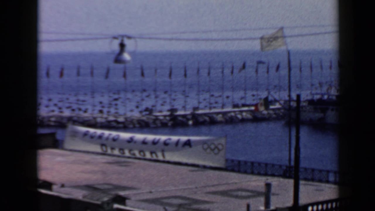 Marina platform with a Porto S. Lucia Dragoni banner, flags, boats and Olympic rings.
