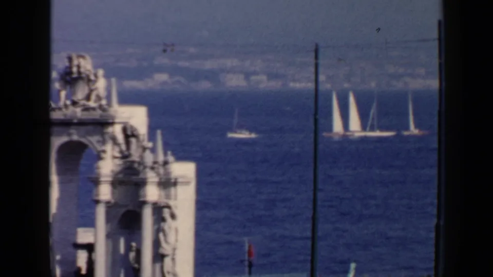 1960 Rome-area bay scene with a foreground stone structure and a group of white sailboats visible offshore.