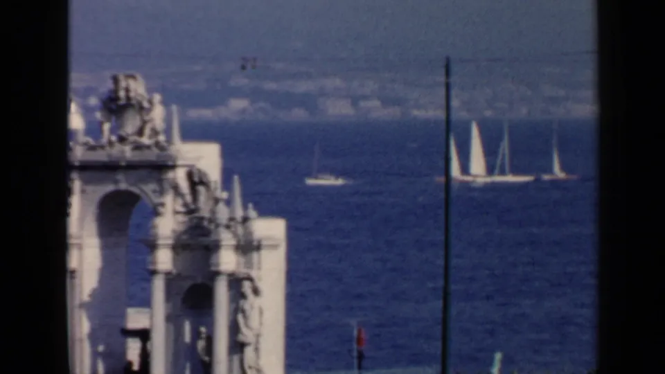 Rome-area 8mm frame showing white sailboats on the bay, a foreground stone structure, and dark film-frame edges.