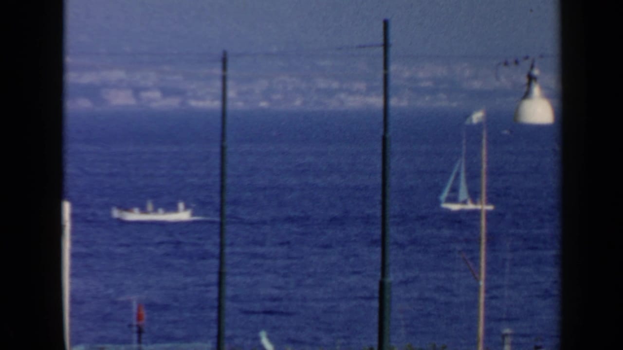 Calm sea with a white boat, sailboat mast, lamp post, and dark framing edges.