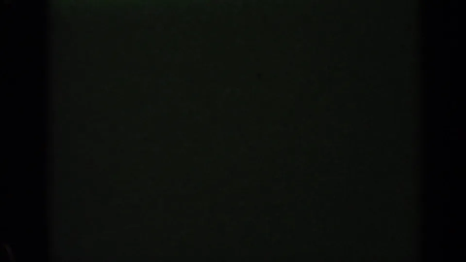End of the 8mm clip showing a mostly dark frame with faint greenish film texture and edge falloff.