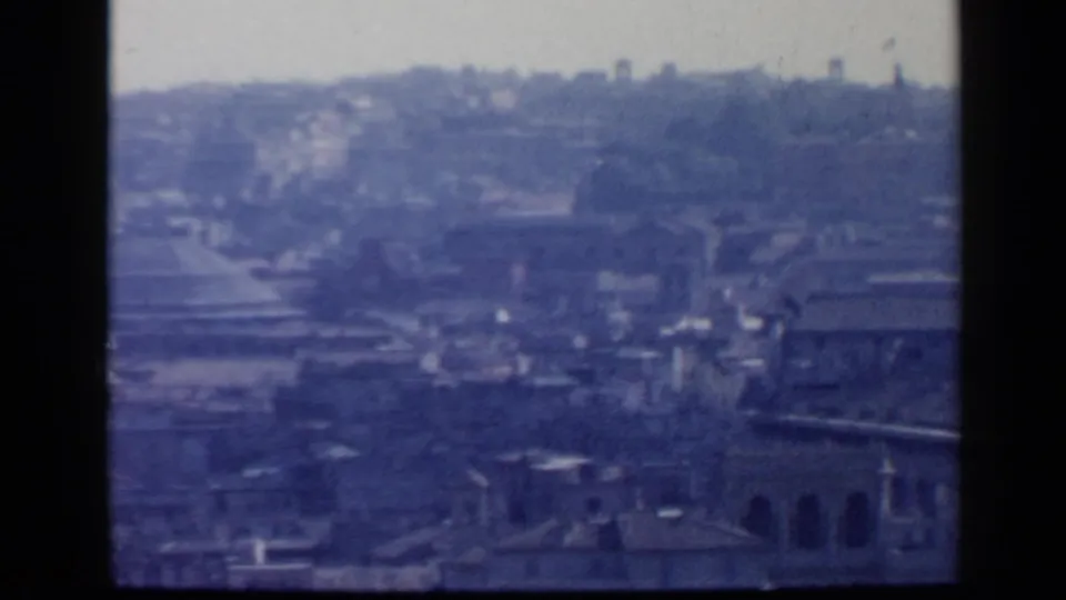 The final 1960 Rome frame holds on a hazy elevated city view with rooftops, distant hillside, arched windows, and blue-shifted film color.