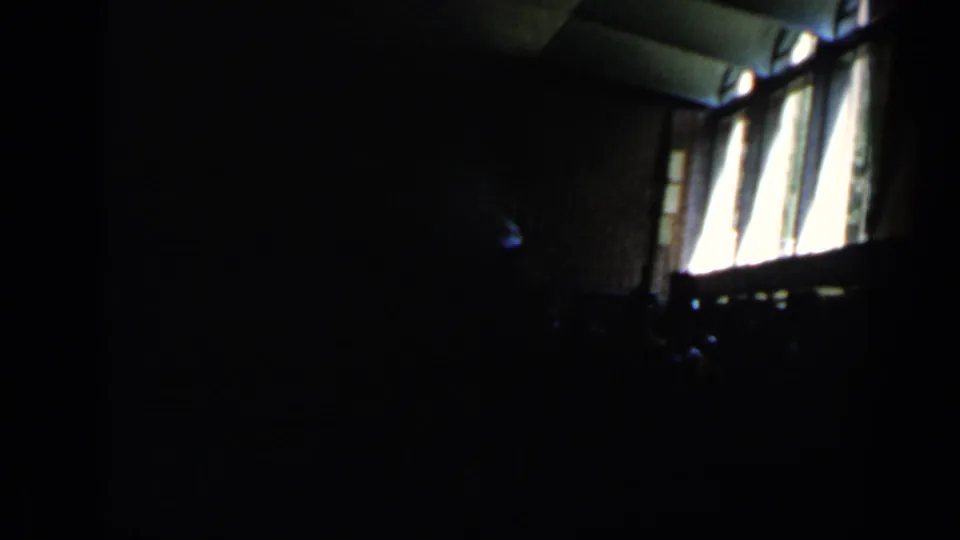 Dim interior frame from the Rome clip, with tall sunlit windows and mostly silhouetted forms in the room.