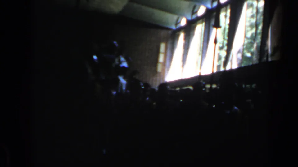 1960 Rome frame with a dim interior crowd, strong window light, and a partially obscured ceremonial figure moving through the hall.