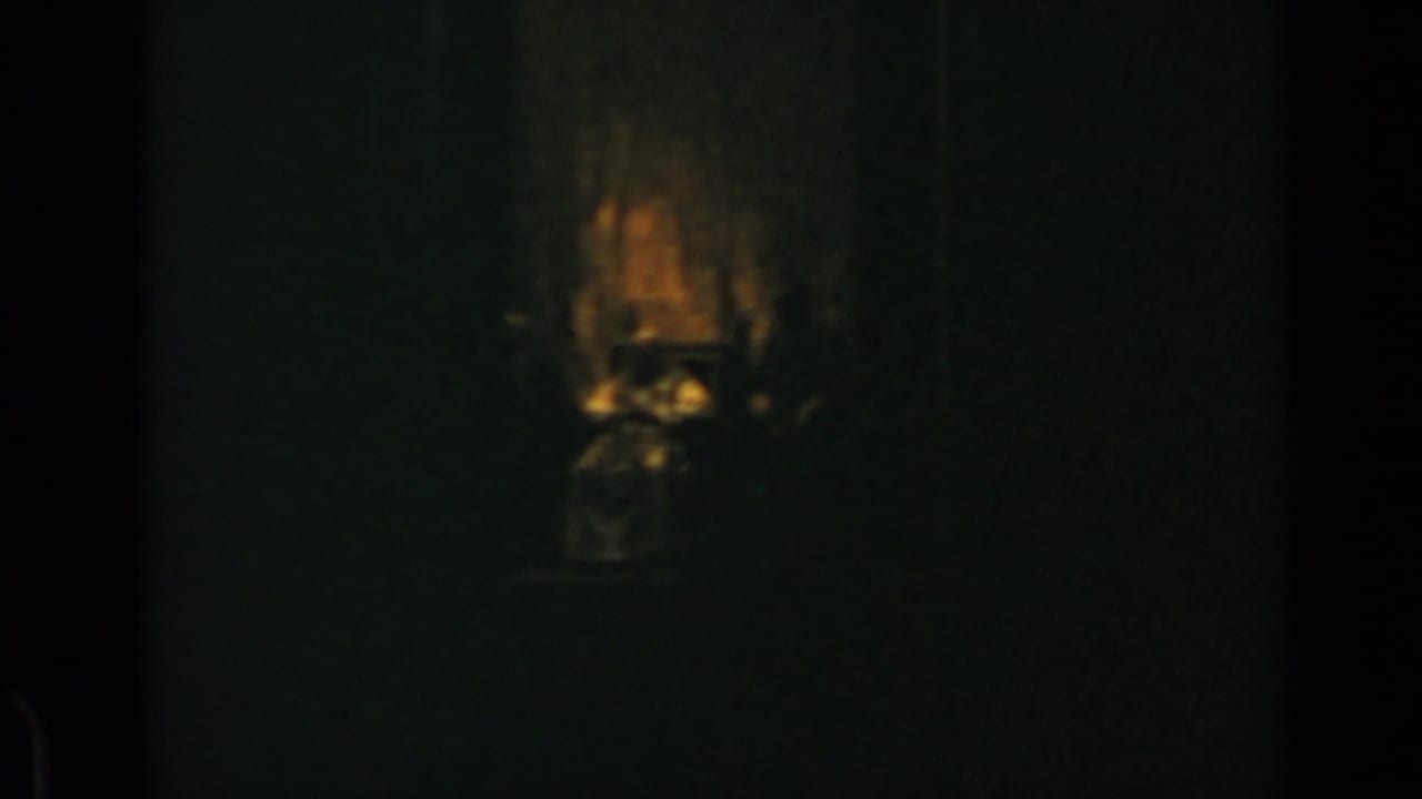 Very dark interior with a warm glow above a shadowed central form.