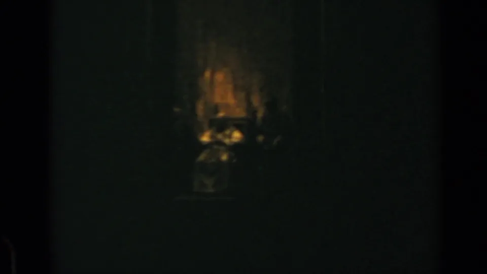 1960 Rome 8mm frame showing a dim interior where a warm flash briefly reveals an indistinct central form.