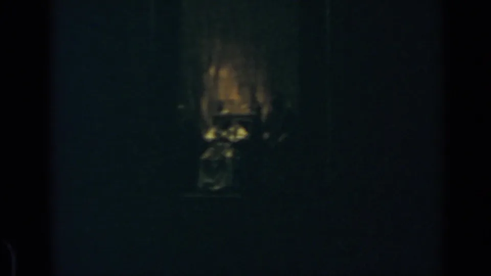 1960 Rome 8mm frame where flickering warm light outlines an indistinct form against a dark interior.