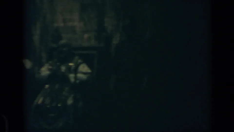 1960 Rome 8mm frame showing a shadowy interior with a faintly lit clustered shape and little surrounding detail.
