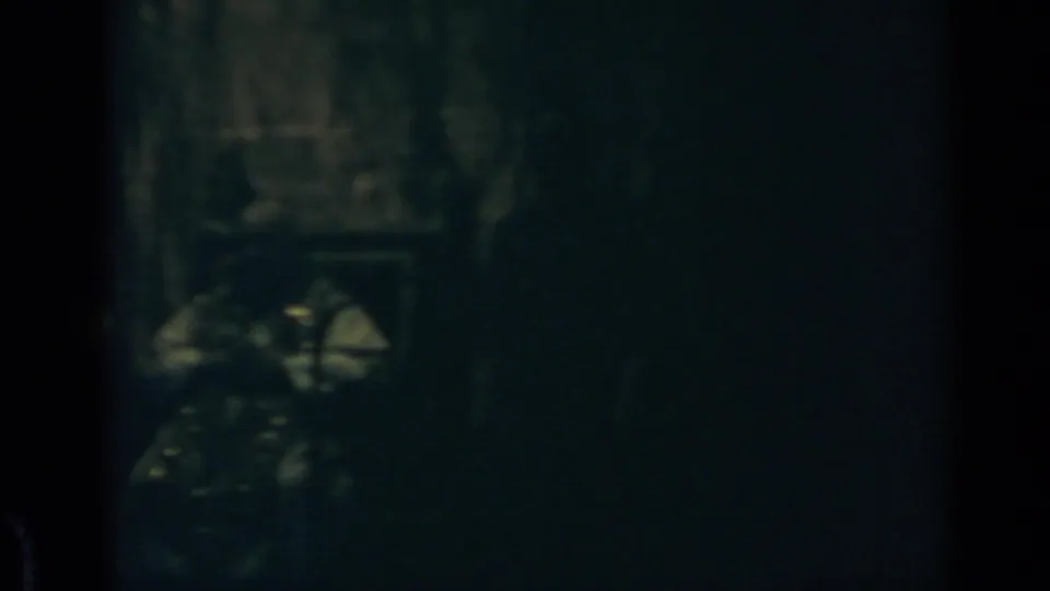 1960 Rome 8mm frame showing a dim interior with heavy shadows and an unclear human form or equipment near the lower left.