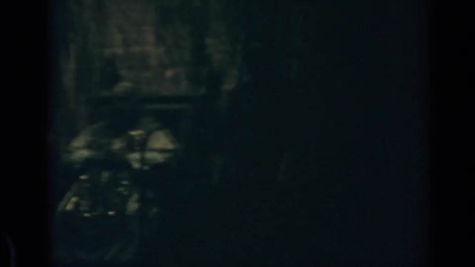 1960 Rome 8mm frame with a faint figure-like shape in a dark, low-exposure interior.