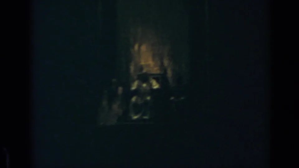 1960 Rome 8mm frame with warm light in a dark interior and indistinct human or object forms below it.