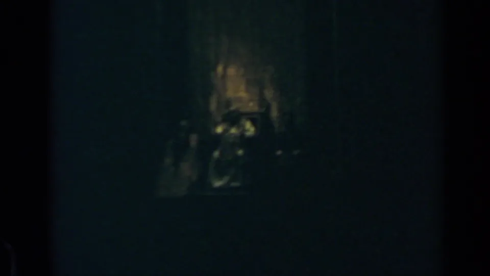 Very dark 1960 Rome 8mm frame with a faint altar-like focal point and little readable detail beyond shadows and grain.