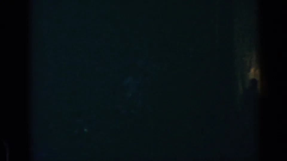 Very dark 8mm frame from Rome with barely visible interior shadows and a small warm highlight near the lower right.