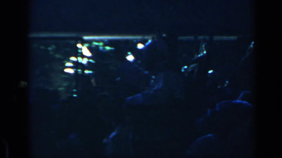 Dark Rome evening show frame with silhouetted audience members and bright blurred lights in the background.