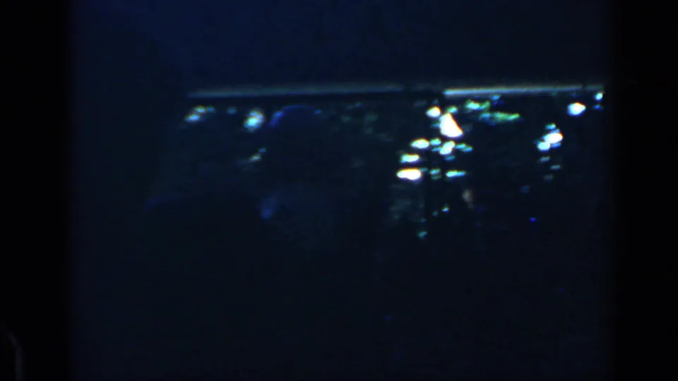 Low-light 1960 Rome frame showing a dense audience and a seated man apparently being carried through the crowd.