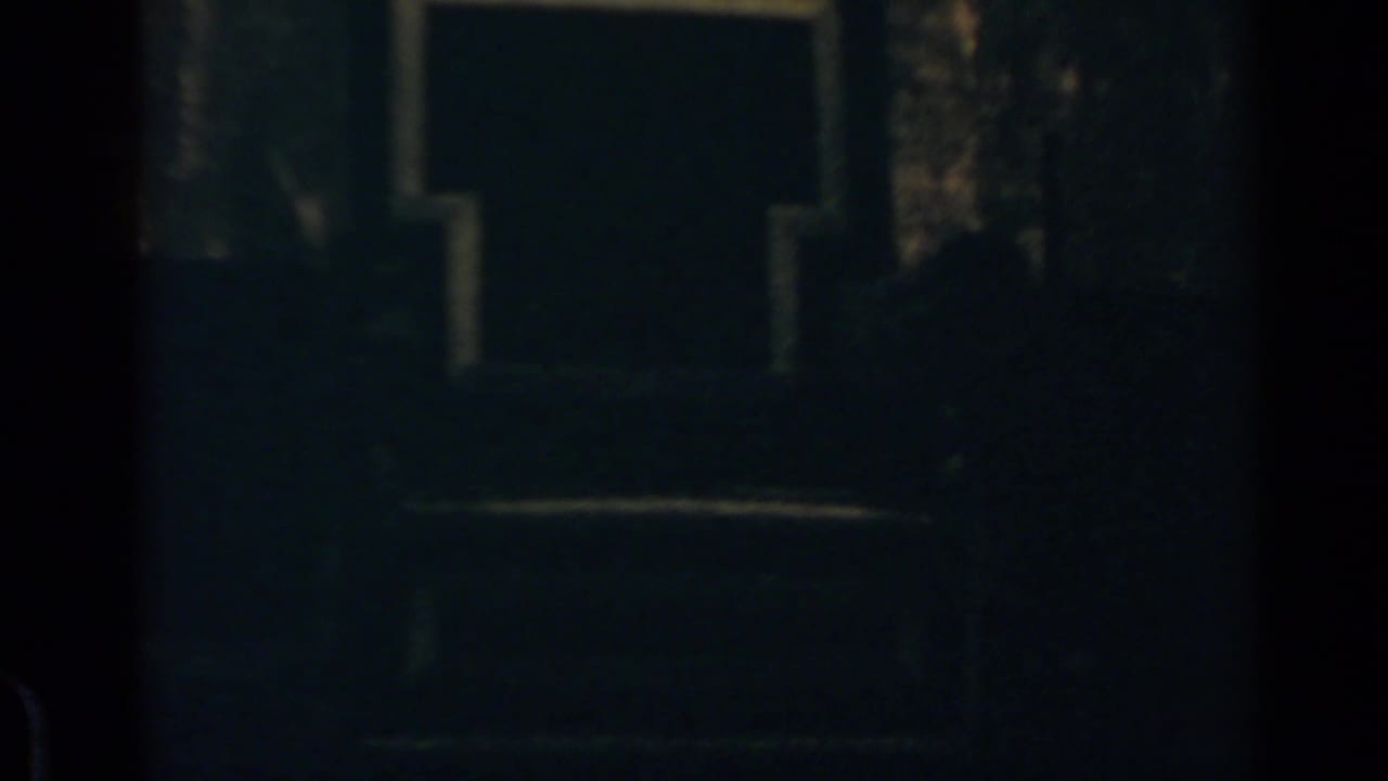 Low-light 8mm frame showing the upper portion of the building and indistinct people below in the Rome crowd scene.
