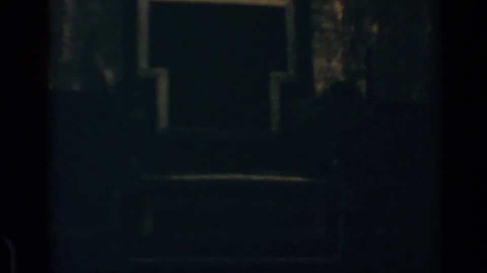 Low-light 8mm frame showing the upper portion of the building and indistinct people below in the Rome crowd scene.