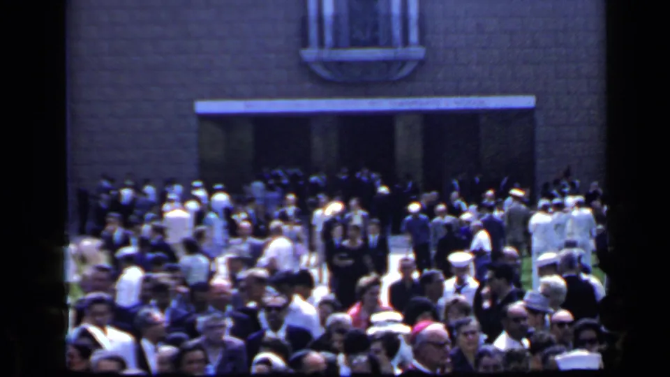 A wider 1960 Rome frame shows the crowd spread across the street outside a stone facade, with white caps and dark suits visible.