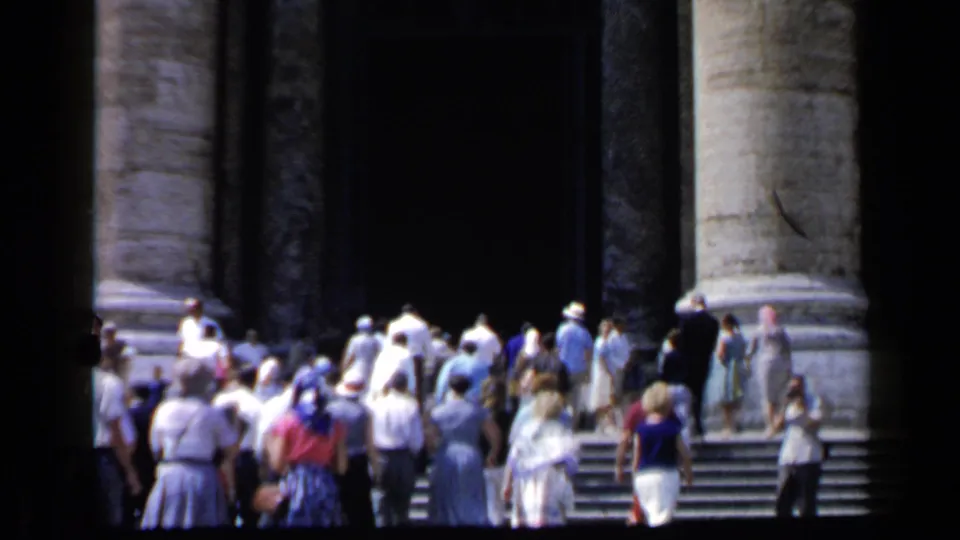 Final Vatican frame with a sunlit tourist crowd climbing steps toward a columned entrance, captured on 8mm film.