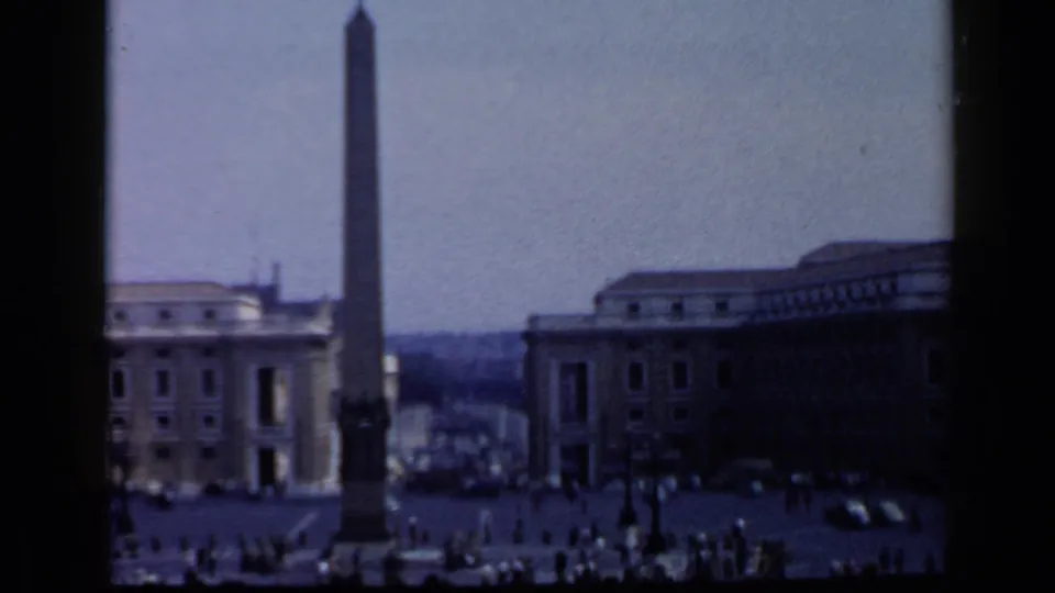 1960 8mm view of St. Peter's Square in Vatican City, showing the obelisk, surrounding buildings, and visitors crossing the plaza.