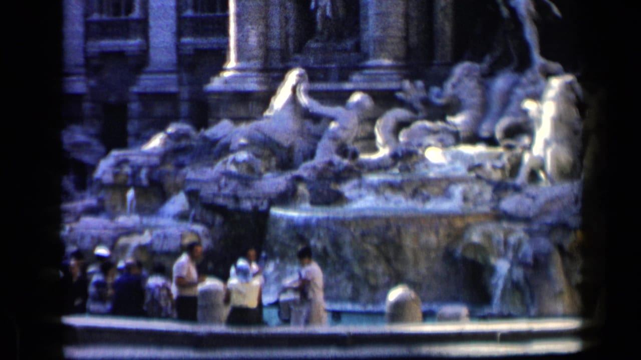 Tourists in period clothing stand at the base of Rome's Trevi Fountain, with large stone figures and water behind them.