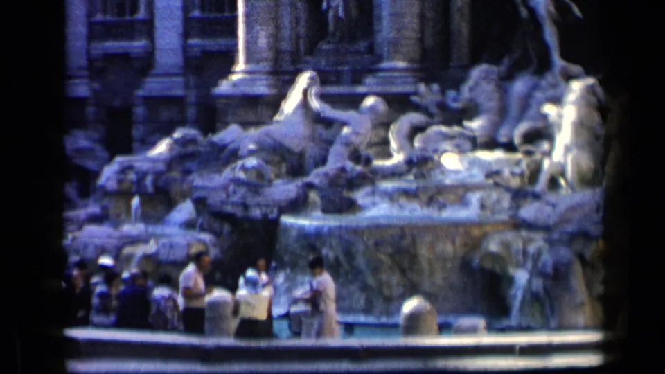 Tourists in period clothing stand at the base of Rome's Trevi Fountain, with large stone figures and water behind them.