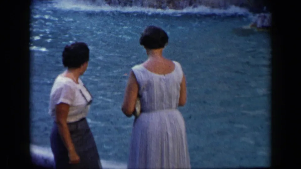 1960 home-movie frame from Vatican, Italy showing two adult women beside water, viewed from behind and side in soft 8mm color.